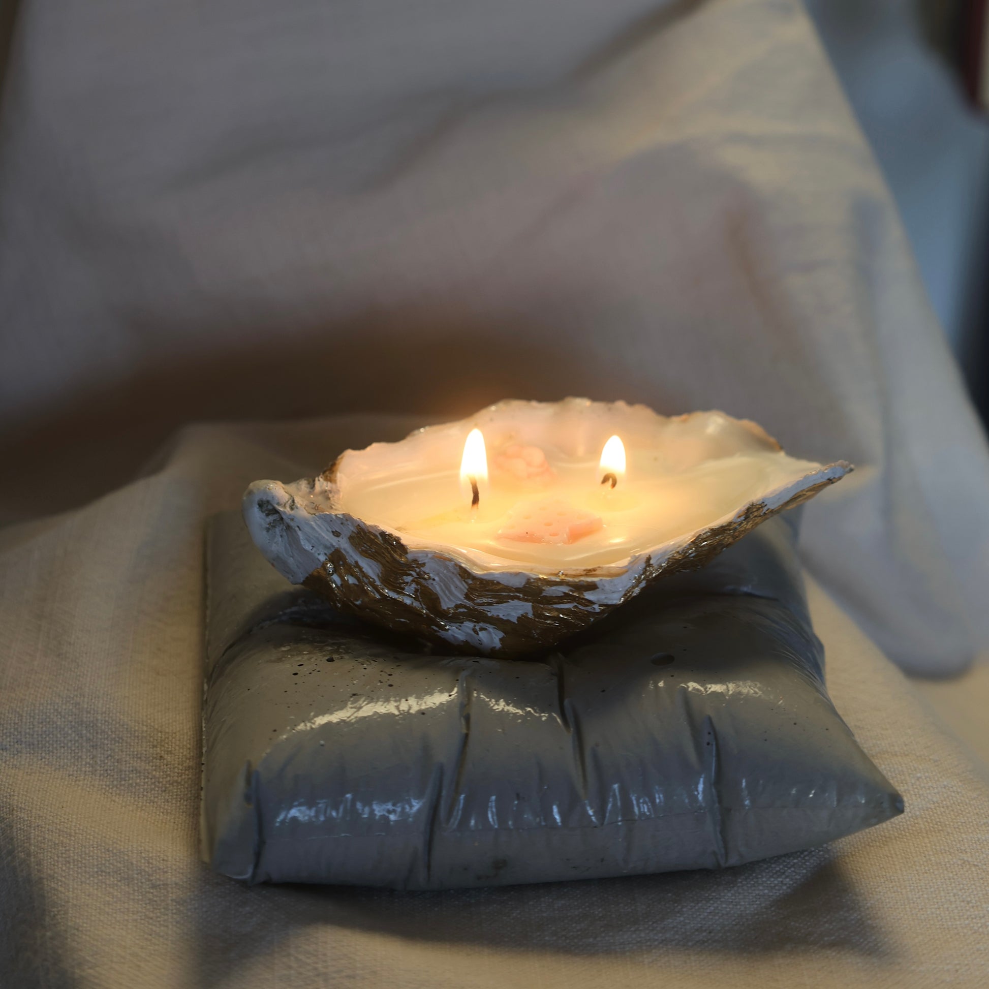 Concrete pillow-shaped candleholder with a glossy finish for displaying a seashell candle by Lily Glow Decor