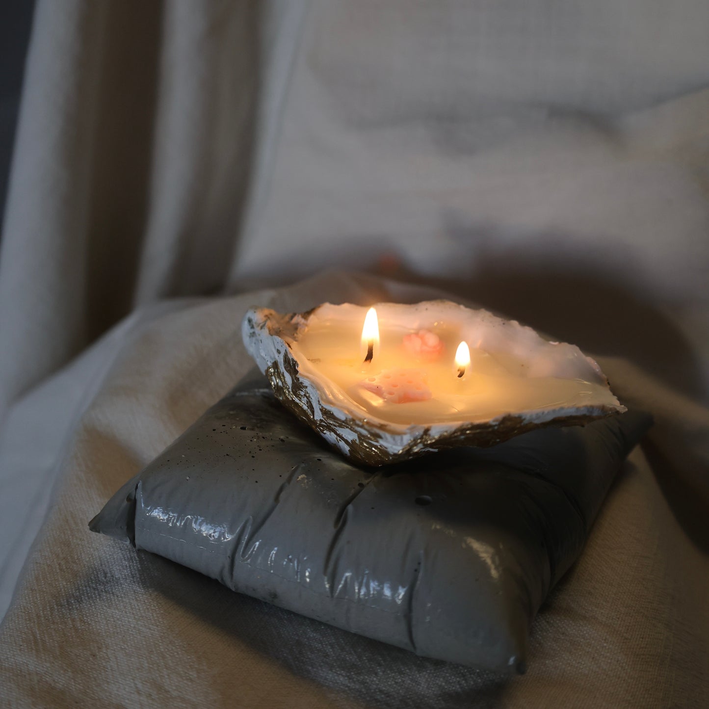 Concrete pillow-shaped candleholder with a glossy finish for displaying a seashell candle by Lily Glow Decor