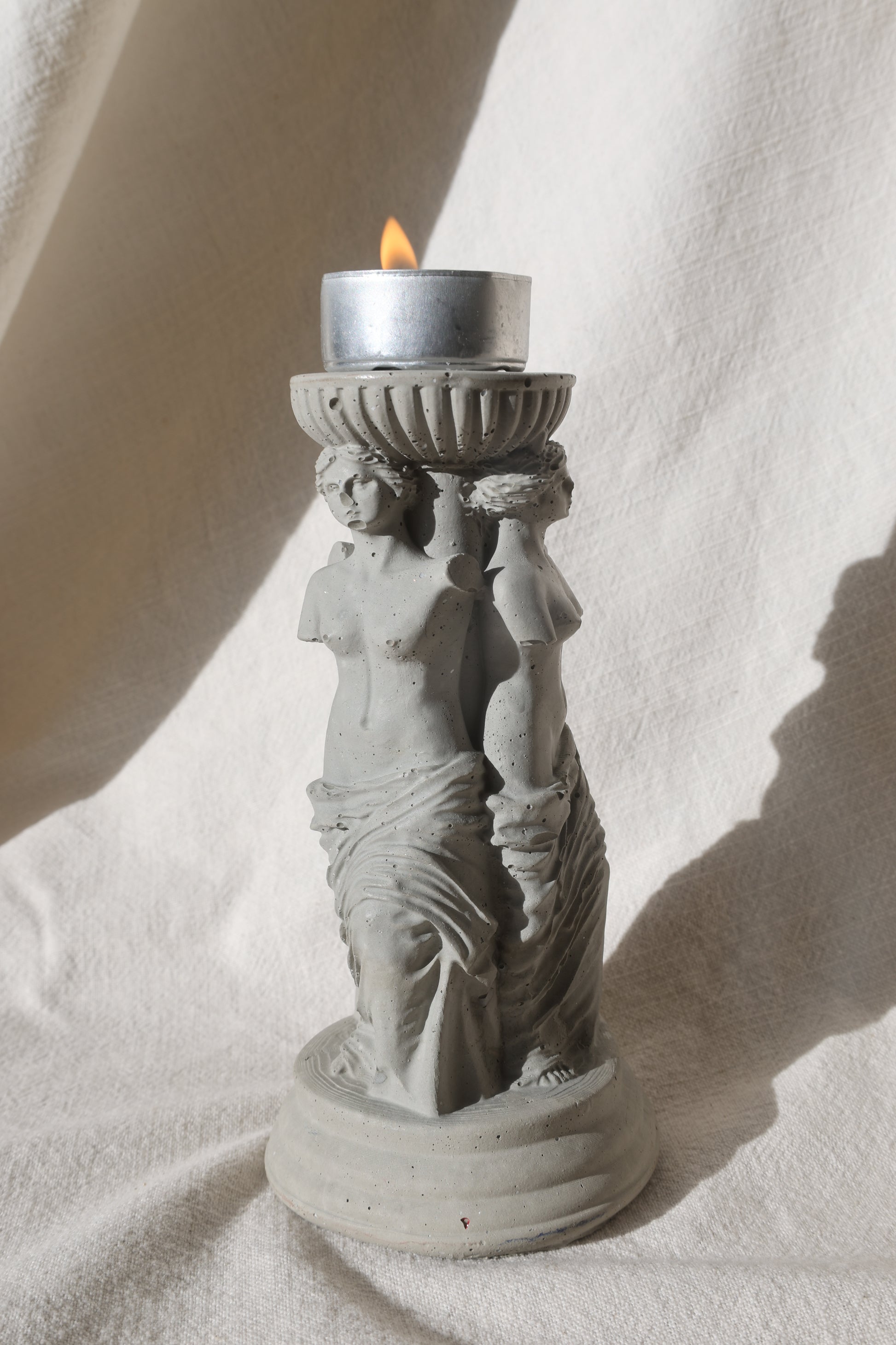 Concrete candle holder with three Venus by Lily Glow Decor figures and a tealight candle