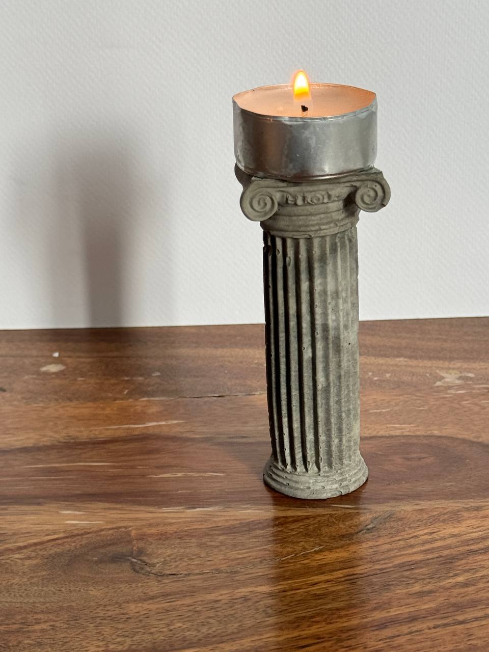 Concrete Ionic column candle holder with a lit tealight on top by Lily Glow Decor