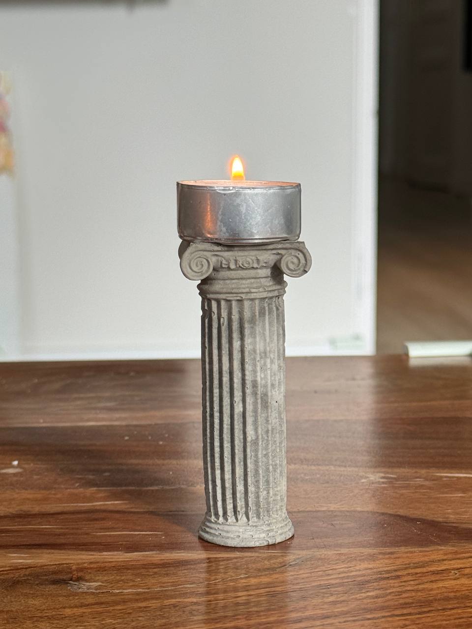 Concrete Ionic column candle holder with a lit tealight on top by Lily Glow Decor