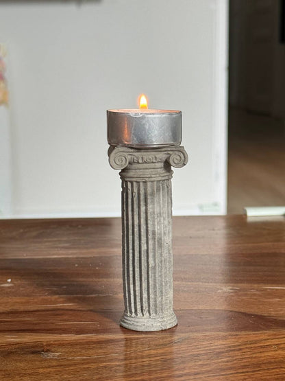 Concrete Ionic column candle holder with a lit tealight on top by Lily Glow Decor