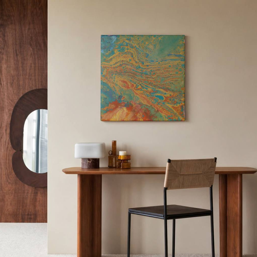 Abstract painting in 30x30 cm format with fluid patterns in blue, green, orange and beige tones, displayed against soft beige fabric by Lily Glow Decor