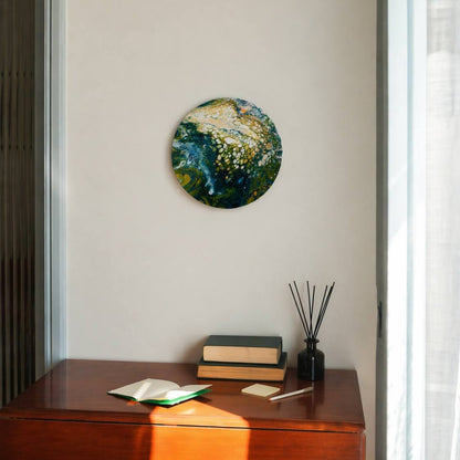 Round abstract painting in shades of green, yellow and white, placed on a marble surface next to home decor pieces by Lily Glow Decor