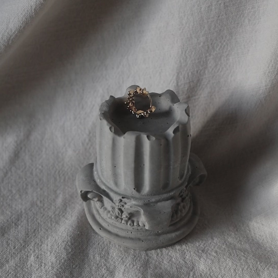 Decorative concrete column candle holder with a lit tealight on neutral fabric background by Lily Glow Decor