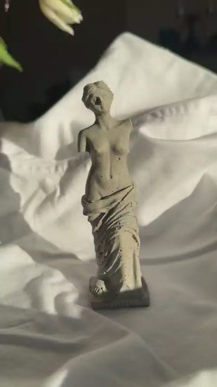 Concrete Venus statue with minimal texture on white fabric background, styled as a decorative element or ring holder.by Lily Glow Decor