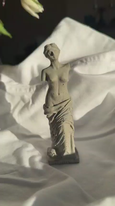 Concrete Venus statue with minimal texture on white fabric background, styled as a decorative element or ring holder.by Lily Glow Decor