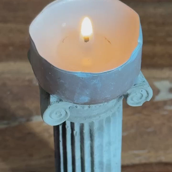 Concrete Ionic column candle holder with a lit tealight on top by Lily Glow Decor