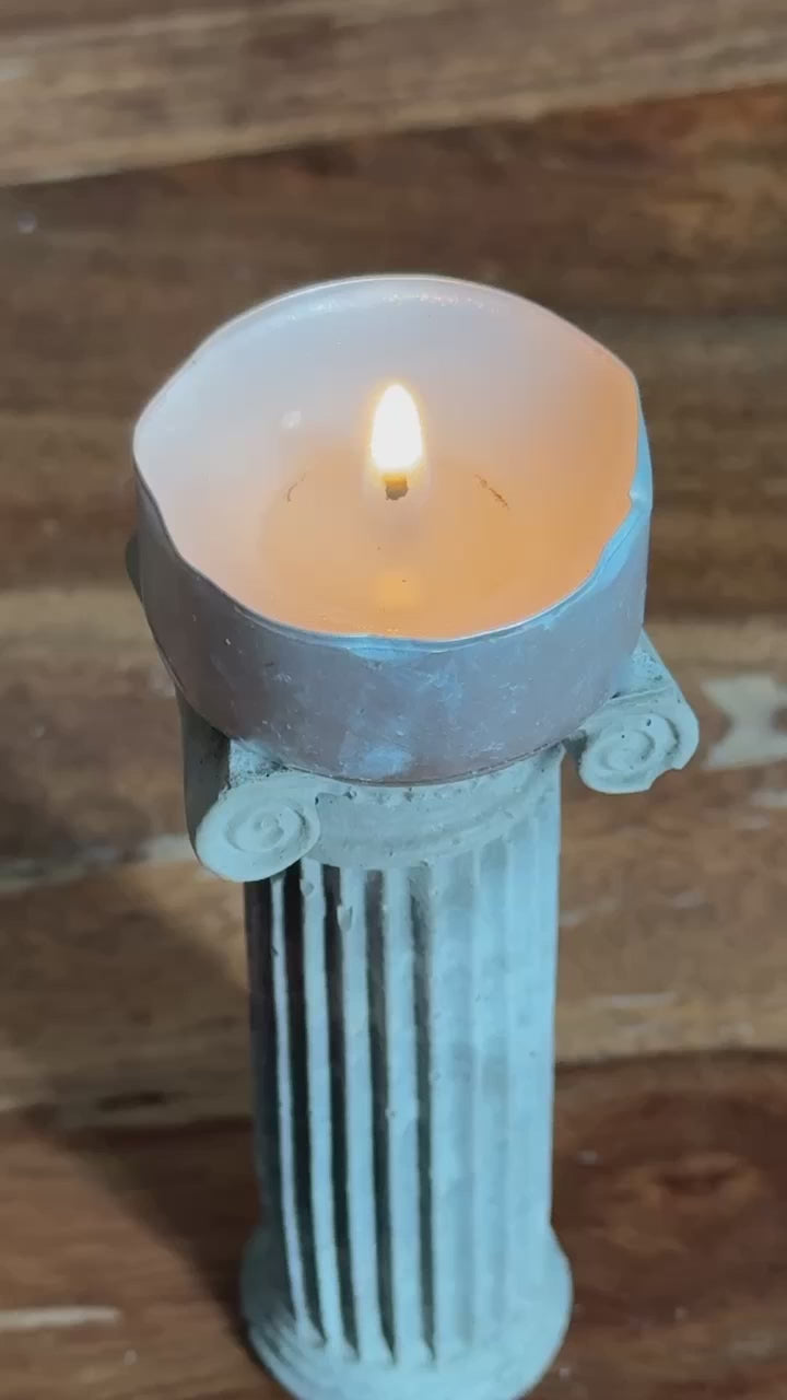 Concrete Ionic column candle holder with a lit tealight on top by Lily Glow Decor